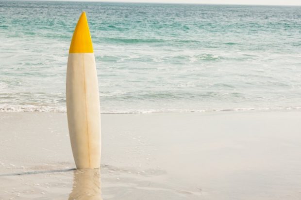 Planche de surf plantée dans le sable sur une plage